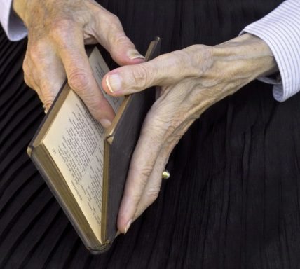 A photo of an elderly persons hands holding a book