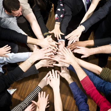 A photo of lots of hands in the centre on top of each other about to cheer.