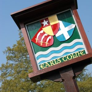 A photo of a village sign with the words "Earls Colne".