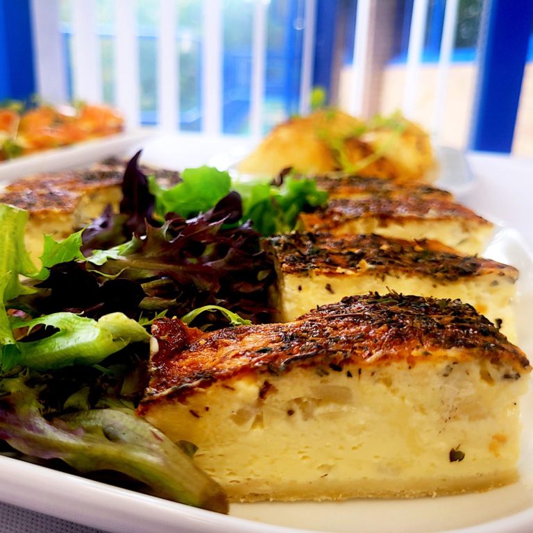 A close up photo of some vintage cheddar cheese and onion quiche fingers and garnish