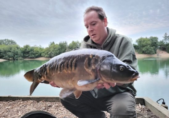 A photo of a man holding a mirror carp.