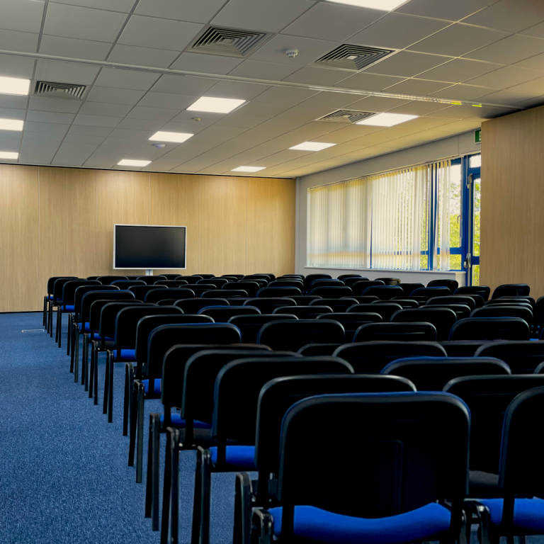 A photo of a large, empty training room, with a theatre layout with around 100 seats