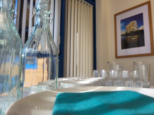 A close up photo of the water bottles, green napkins, plates, and glasses in the boardroom.