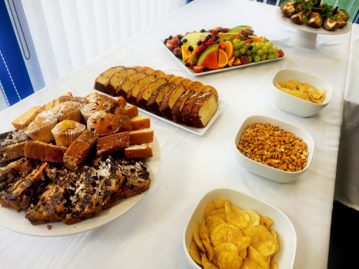 A photo of the cakes, crisps, nuts, and fruit platter on a table with a white table cloth.