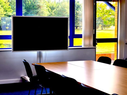 A close up photo of a boardroom layout meeting room with a focus on the 65" interactive smart screen flip TV