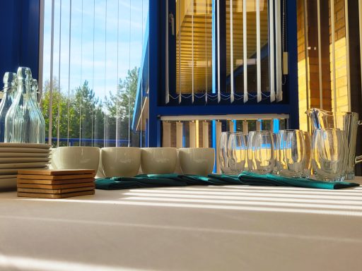 A photo of the refreshments table in the boardroom with cups, plates, glasses, and water bottles and jugs on the table.