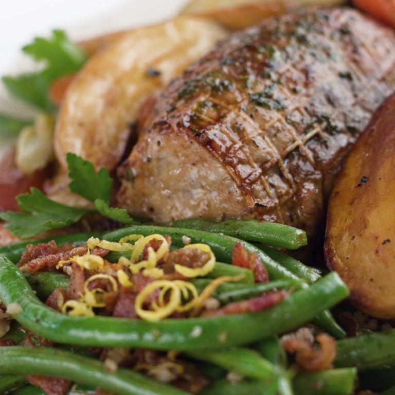 A photo of fine dining main dish with a large cut of meat and vegetables.