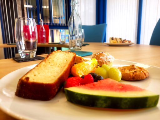 A close up of a selection of cakes and fruit on a plate in the boardroom.