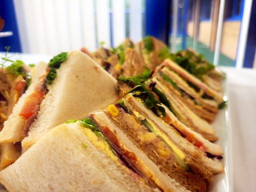 A close up of a sandwich platter with triangle sandwiches with various fillings.