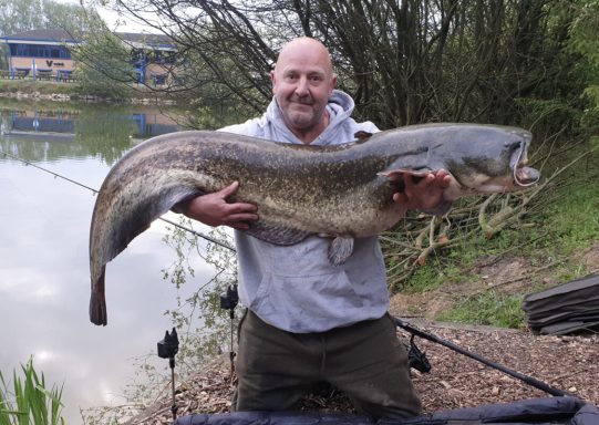 An angler holding up a large catfish