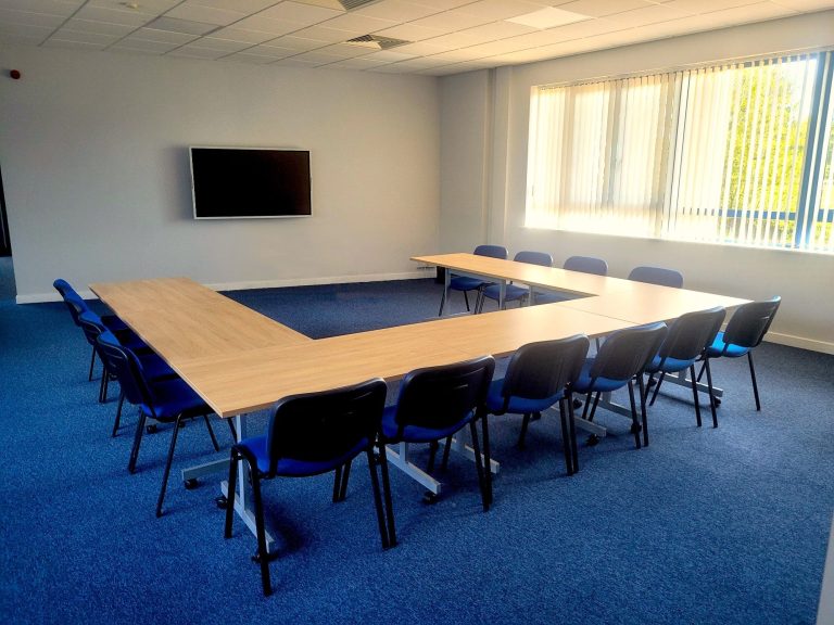 A training room with a u-shape layout with large screen on the wall