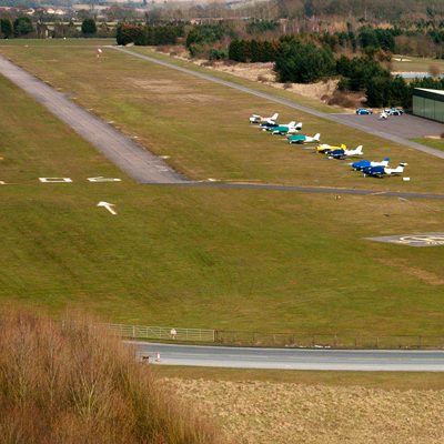 A photo of an airfield with a runway and several small planes.