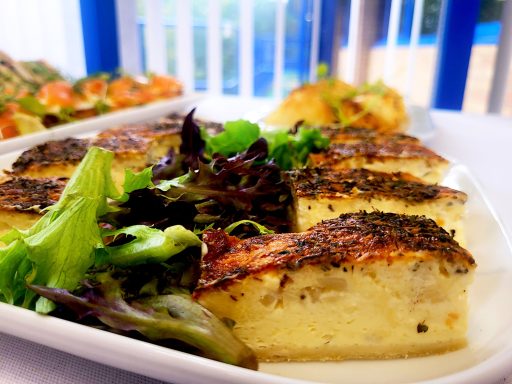 A close up photo of a plate of vintage cheese and onion quiche fingers with leafy lettuce garnish