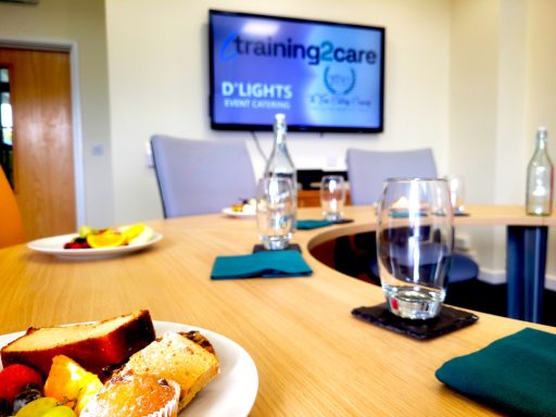 A photo of a boardroom with glass water bottles, glasses, and plates of food on the table.