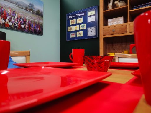 A close up of the red plates and glasses on the table in the dining room film set.