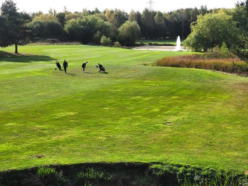 A photo of two people playing golf on a sunny day on the hole of the course next to the venue.