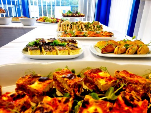 A photo of various plates from a buffet including quiches and Cornish pasties