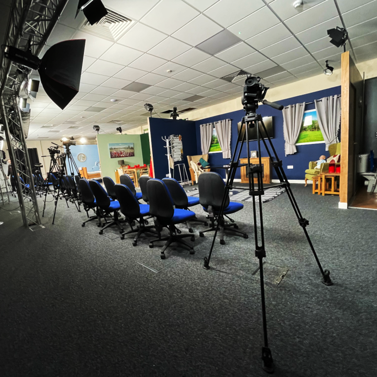 A photo of a film studio and equipment, chairs, and the sets.