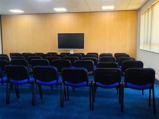 A photo of an empty theatre style meeting room with large interactive screen.