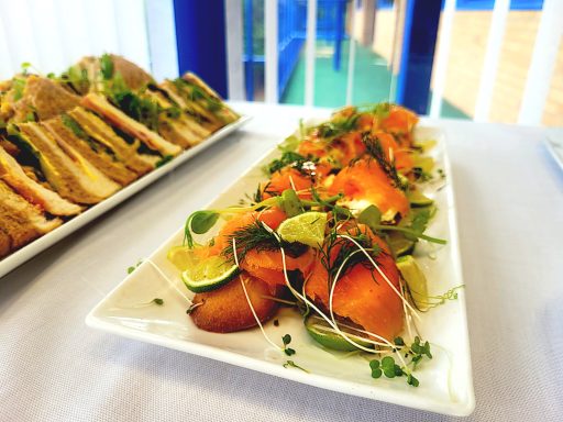 A photo of smoked salmon crostini and a platter of sandwiches.