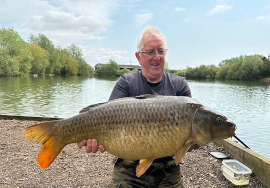 A photo of a fisherman holding a large common carp.