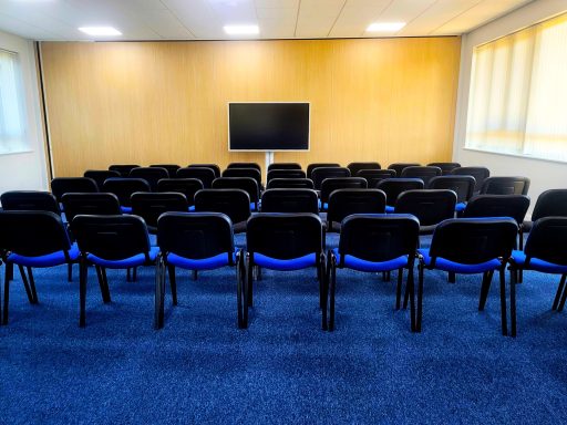 An empty theatre style training room with 45 chairs focusing on a 65" smart screen.