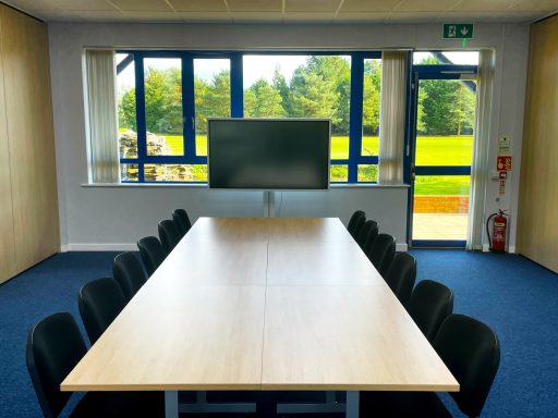 A photo of the boardroom layout in meeting room 2 with the 65" smart screen in front of the window overlooking the golf course and fountain