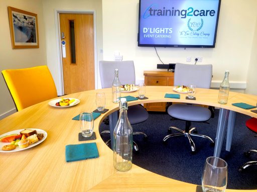 A photo of the round boardroom table with water bottles, glasses, and plates of buffet food around it.