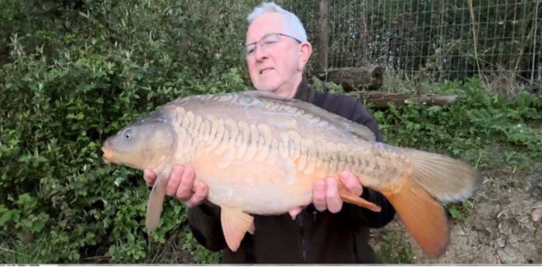 An angler holding a large mirror carp