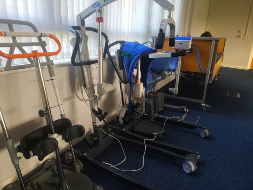 A photo of health & social care equipment including a hoist, stand assist, and bed.