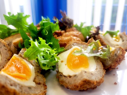 A close up photo of homemade scotch eggs with leafy garnish