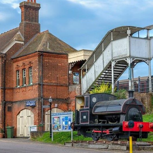 A photo of a small railway station with a footbridge.