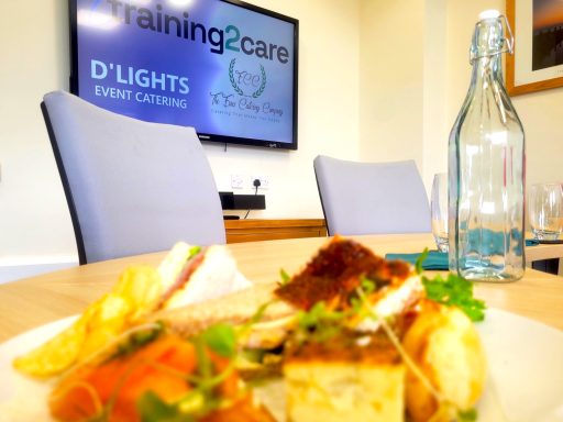 A photo in the boardroom with a blurred plate of food in the foreground and the TV clear in the background with company logos on it.